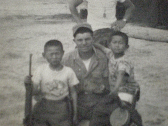 Showing his rifle to two Korean children